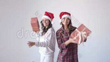 穿着圣诞帽和睡衣跳舞和摇动礼盒的快乐女人。 假日概念，惊喜
